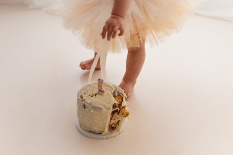 Photograph shows a young girl reaching for her cake during a cake smash photoshoot in West Malling, Kent