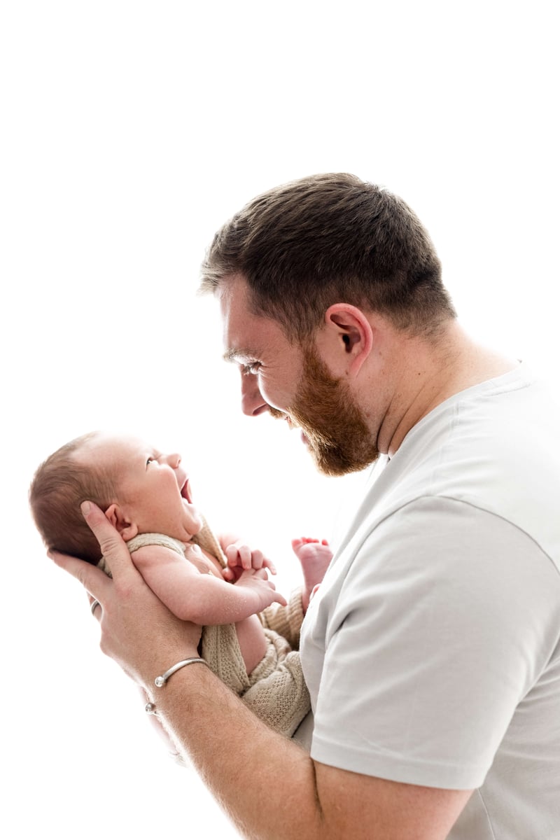 Newborn baby and dad looking at each other smiling and laughing for the homepage banner