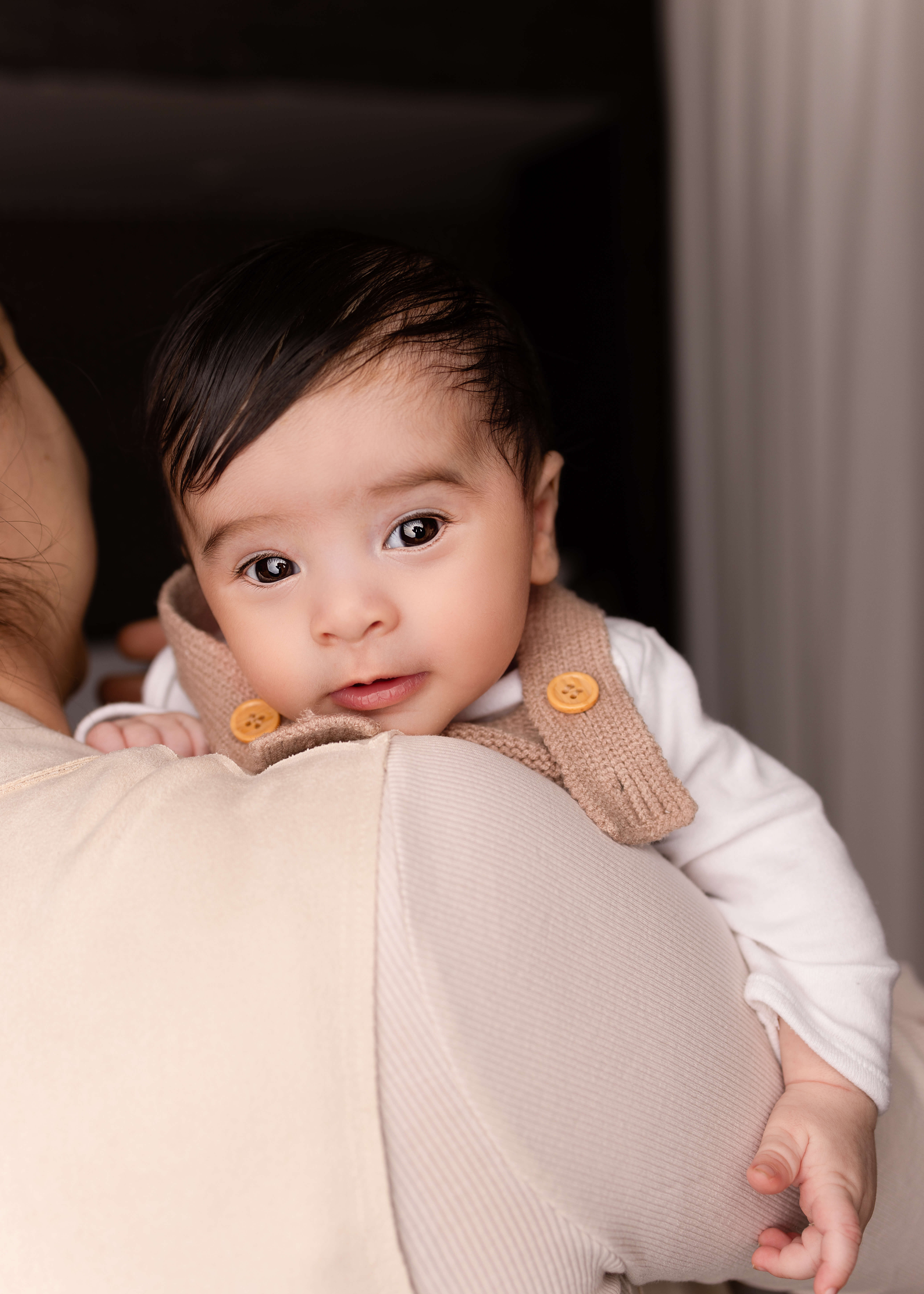 Newborn photography outfits, showing a baby wearing a white long-sleeved t-shirt and soft knit jumper being carried