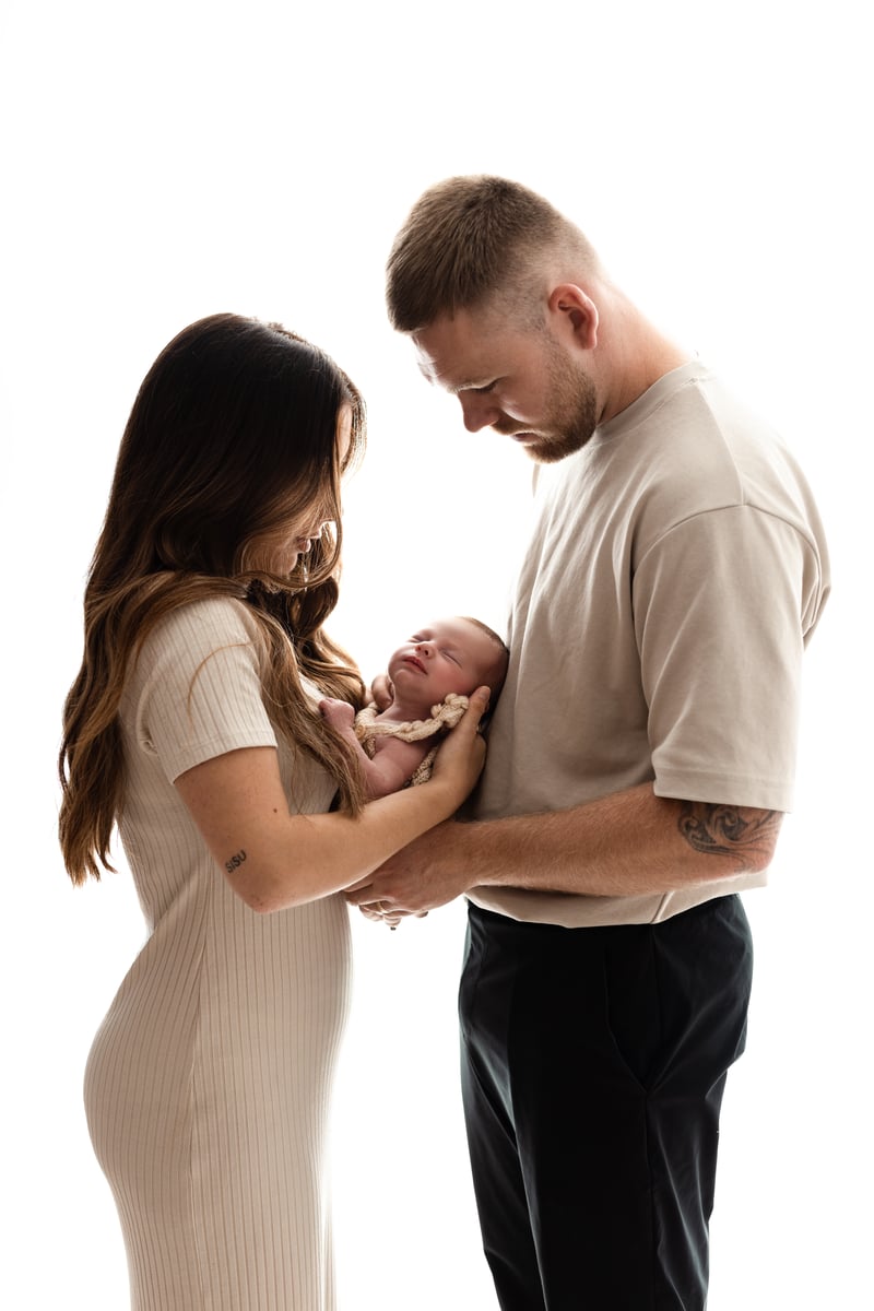 Mum and dad holding newborn baby in photoshoot