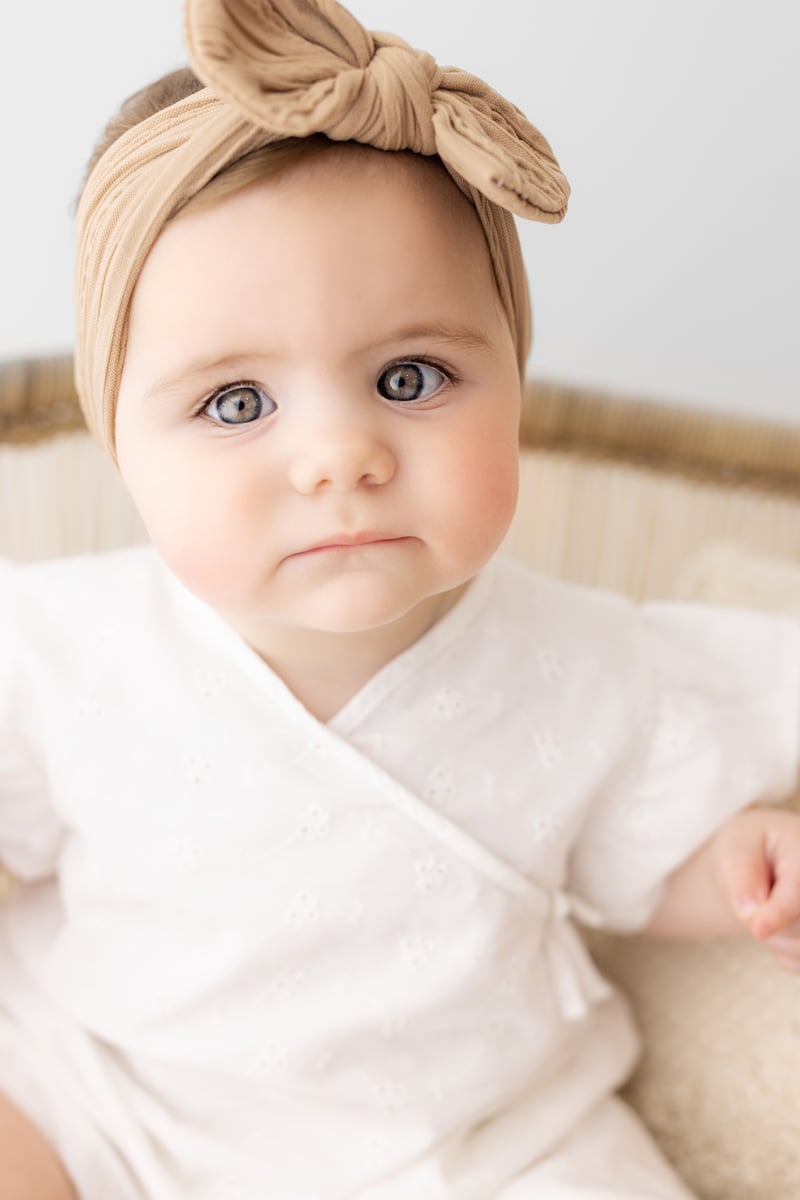 baby photoshoot with bow, looking into the camera