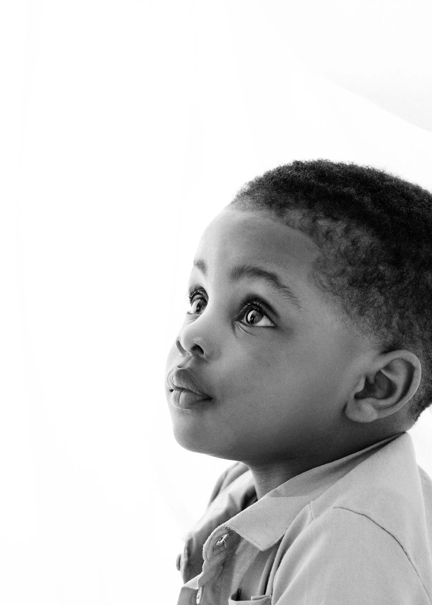 Black and white portrait of a young boy looking upwards, with expressive eyes and soft light.